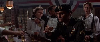 Movie still from “The Deer Hunter” (1978), directed by Michael Cimino – A group of men sitting at a table with drinks; Medium shot, Over the shoulder angle