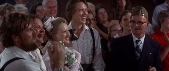 Movie still from “The Deer Hunter” (1978), directed by Michael Cimino – A man and woman are smiling while standing in front of a crowd; Close Up shot, Low angle