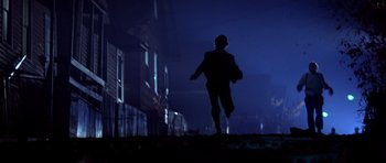 Movie still from “The Deer Hunter” (1978), directed by Michael Cimino – A man is running in the dark with a helmet on his head; Wide shot, Low angle