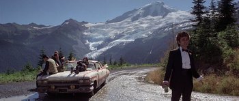 Movie still from “The Deer Hunter” (1978), directed by Michael Cimino – A car driving down a road near a mountain range; Extreme Wide shot, Low angle