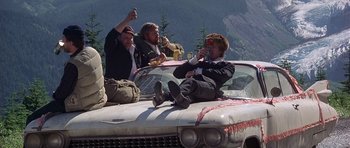 Movie still from “The Deer Hunter” (1978), directed by Michael Cimino – A group of people sitting on the hood of a car; Wide shot, Low angle