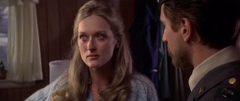 Movie still from “The Deer Hunter” (1978), directed by Michael Cimino – A young woman looking at the camera while a man looks on; Close Up shot, Over the shoulder angle
