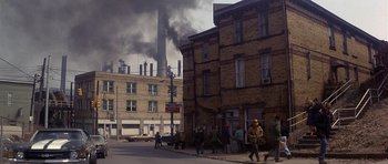Movie still from “The Deer Hunter” (1978), directed by Michael Cimino – People walking down the street in front of a factory; Extreme Wide shot, High angle