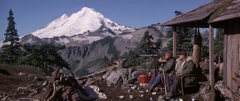 Movie still from “The Deer Hunter” (1978), directed by Michael Cimino – A man sitting on top of a mountain looking through a telescope; Wide shot, Low angle