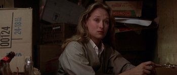 Movie still from “The Deer Hunter” (1978), directed by Michael Cimino – A woman sitting at a table in a room with boxes; Close Up shot, Over the shoulder angle