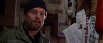 Movie still from “The Deer Hunter” (1978), directed by Michael Cimino – A person wearing a hat near a phone; Close Up shot, Over the shoulder angle