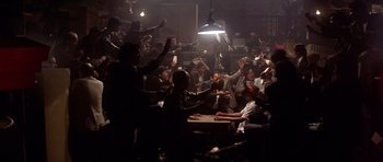 Movie still from “The Deer Hunter” (1978), directed by Michael Cimino – A group of people sitting at a table in a dark room; Extreme Wide shot, High angle