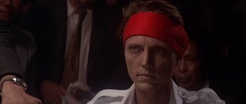 Movie still from “The Deer Hunter” (1978), directed by Michael Cimino – A man wearing a red head band and looking at the camera; Close Up shot, Over the shoulder angle