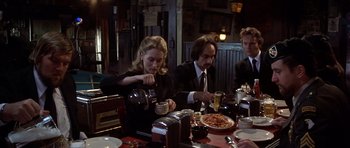 Movie still from “The Deer Hunter” (1978), directed by Michael Cimino – A group of people sitting at a table eating pizza; Medium shot, High angle