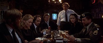 Movie still from “The Deer Hunter” (1978), directed by Michael Cimino – A group of people sitting at a table with drinks; Medium shot, Low angle