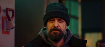 Movie still from “10 Days of a Bad Man” (2023), directed by Uluç Bayraktar – A man with a beard wearing a black hat; Close Up shot, Low angle