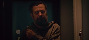 Movie still from “10 Days of a Bad Man” (2023), directed by Uluç Bayraktar – A man with a long beard and a sweater on; Close Up shot, Low angle