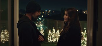 Movie still from “10 Days of a Bad Man” (2023), directed by Uluç Bayraktar – A man and a woman standing next to each other in front of lights; Close Up shot, Over the shoulder angle