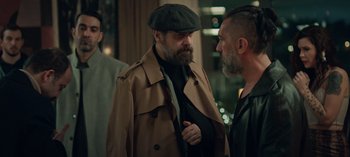 Movie still from “10 Days of a Bad Man” (2023), directed by Uluç Bayraktar – A man in a hat and a jacket talking to another man in a jacket; Medium shot, Over the shoulder angle