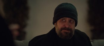 Movie still from “10 Days of a Bad Man” (2023), directed by Uluç Bayraktar – A man with a beard wearing a black hat; Close Up shot, Over the shoulder angle