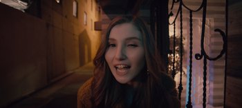 Movie still from “10 Days of a Bad Man” (2023), directed by Uluç Bayraktar – A young woman smiling for the camera in the dark; Close Up shot, Low angle