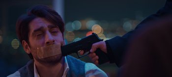 Movie still from “10 Days of a Bad Man” (2023), directed by Uluç Bayraktar – A man is being held up by a gun; Close Up shot, Over the shoulder angle