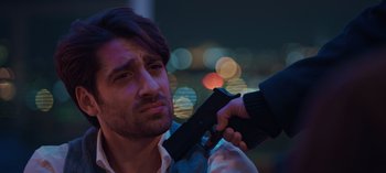 Movie still from “10 Days of a Bad Man” (2023), directed by Uluç Bayraktar – A man holding a gun up to his face; Close Up shot, Over the shoulder angle
