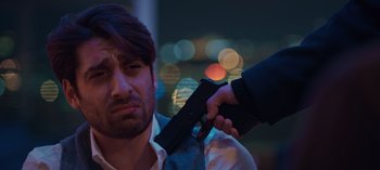 Movie still from “10 Days of a Bad Man” (2023), directed by Uluç Bayraktar – A man holding a gun up to his face; Close Up shot, Over the shoulder angle