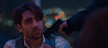 Movie still from “10 Days of a Bad Man” (2023), directed by Uluç Bayraktar – A man holding a gun up to his face; Close Up shot, Over the shoulder angle