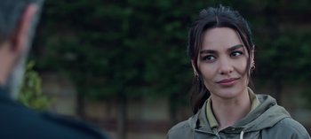 Movie still from “10 Days of a Bad Man” (2023), directed by Uluç Bayraktar – A person wearing a jacket with trees in the background; Close Up shot, Over the shoulder angle