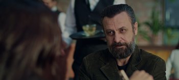 Movie still from “10 Days of a Bad Man” (2023), directed by Uluç Bayraktar – A man with a goatee sitting in front of another man with a goatee; Close Up shot, Over the shoulder angle