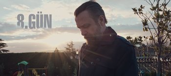 Movie still from “10 Days of a Bad Man” (2023), directed by Uluç Bayraktar – A person wearing a jacket near a forest; Close Up shot, Low angle