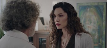 Movie still from “10 Days of a Bad Man” (2023), directed by Uluç Bayraktar – A woman with long curly hair wearing a necklace; Close Up shot, Over the shoulder angle