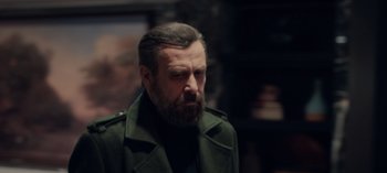 Movie still from “10 Days of a Bad Man” (2023), directed by Uluç Bayraktar – A man with a beard wearing a green jacket; Medium shot, Over the shoulder angle