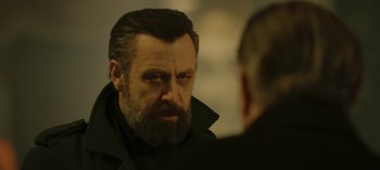 Movie still from “10 Days of a Bad Man” (2023), directed by Uluç Bayraktar – A man with a beard looking at his reflection in a mirror; Close Up shot, Over the shoulder angle