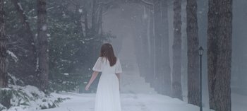 Movie still from “10 Days of a Bad Man” (2023), directed by Uluç Bayraktar – A woman in a white dress walking down a snow covered path; Wide shot, Low angle