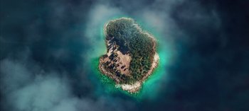 Movie still from “10 Days of a Good Man” (2023), directed by Uluç Bayraktar – An aerial view of an island in the middle of the ocean; Extreme Wide shot, Overhead angle