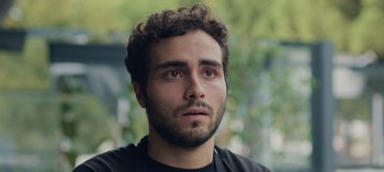 Movie still from “10 Days of a Good Man” (2023), directed by Uluç Bayraktar – A person with curly hair looking at the camera; Close Up shot, Low angle