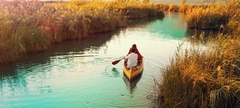 Movie still from “10 Days of a Good Man” (2023), directed by Uluç Bayraktar – Two people in a canoe on a small river; Extreme Wide shot, High angle