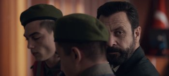 Movie still from “10 Days of a Good Man” (2023), directed by Uluç Bayraktar – A group of men standing next to each other in a room; Close Up shot, Over the shoulder angle