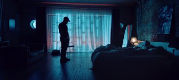 Movie still from “10 Days of a Good Man” (2023), directed by Uluç Bayraktar – A man standing in front of a bed in a room; Wide shot, Low angle