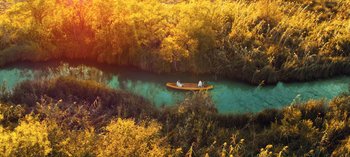 Movie still from “10 Days of a Good Man” (2023), directed by Uluç Bayraktar – Two people in a canoe on a river; Extreme Wide shot, High angle