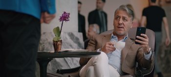 Movie still from “10 Days of a Good Man” (2023), directed by Uluç Bayraktar – A person sitting in a chair holding a coffee cup; Medium shot, Over the shoulder angle