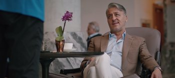 Movie still from “10 Days of a Good Man” (2023), directed by Uluç Bayraktar – A person sitting in a chair near a table; Medium shot, Over the shoulder angle