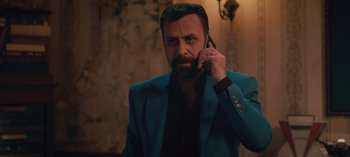 Movie still from “10 Days of a Good Man” (2023), directed by Uluç Bayraktar – A man in a blue jacket talking on a cell phone; Medium shot, Low angle