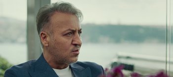 Movie still from “10 Days of a Good Man” (2023), directed by Uluç Bayraktar – A person wearing a suit and tie; Close Up shot, Low angle