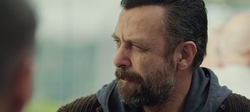 Movie still from “10 Days of a Good Man” (2023), directed by Uluç Bayraktar – A person with a beard; Close Up shot, Over the shoulder angle