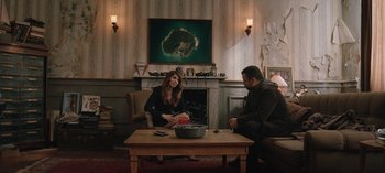 Movie still from “10 Days of a Good Man” (2023), directed by Uluç Bayraktar – A man and a woman sitting in a living room next to a fireplace; Wide shot, High angle