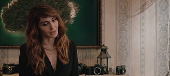 Movie still from “10 Days of a Good Man” (2023), directed by Uluç Bayraktar – A woman with red hair is sitting in front of a painting; Close Up shot, Over the shoulder angle