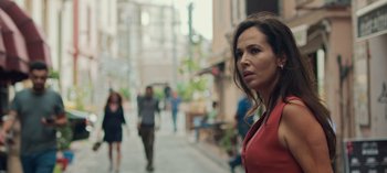 Movie still from “10 Days of a Good Man” (2023), directed by Uluç Bayraktar – A woman standing on a sidewalk in front of a crowd of onlookers; Close Up shot, Low angle