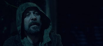 Movie still from “10 Days of a Good Man” (2023), directed by Uluç Bayraktar – A man with a beard and a hooded jacket looking to his left; Close Up shot, Over the shoulder angle