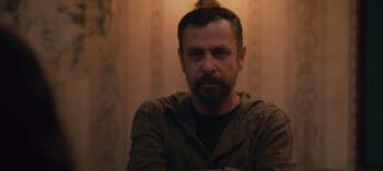 Movie still from “10 Days of a Good Man” (2023), directed by Uluç Bayraktar – A person sitting in a room; Close Up shot, Low angle