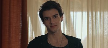 Movie still from “10 Days of a Good Man” (2023), directed by Uluç Bayraktar – A young man with long dark hair wearing a black shirt; Close Up shot, Low angle