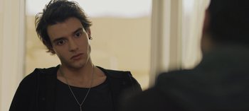 Movie still from “10 Days of a Good Man” (2023), directed by Uluç Bayraktar – A young man with long black hair wearing a black jacket; Close Up shot, Over the shoulder angle