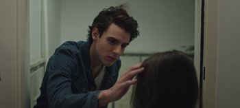 Movie still from “10 Days of a Good Man” (2023), directed by Uluç Bayraktar – A young man looking into a mirror while touching a woman's hair; Close Up shot, Over the shoulder angle